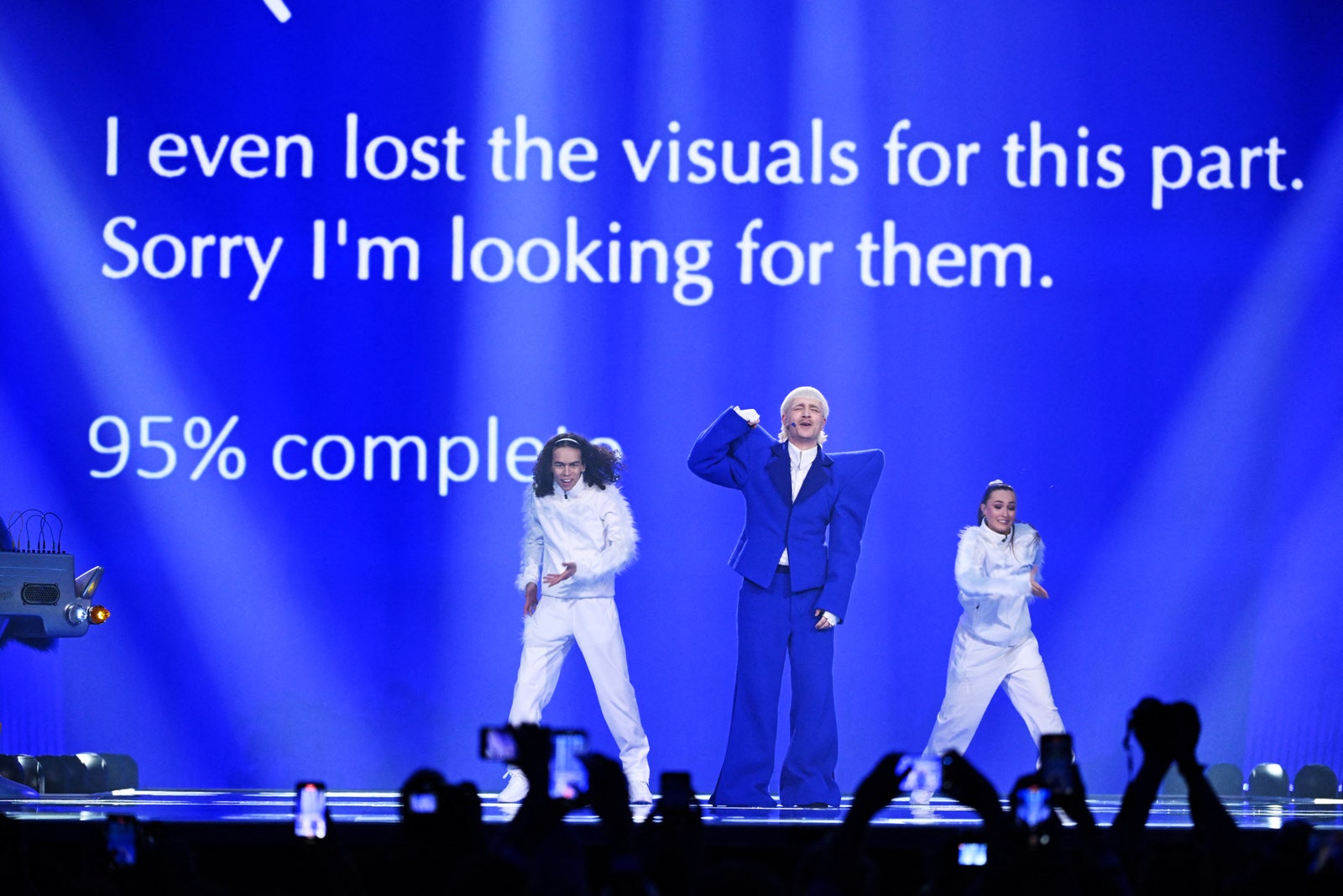 L'image contient peut-être Personne adulte Vêtements de scène Manteau Groupe Représentation Éclairage Foule Personnes Blazer Veste et chapeau