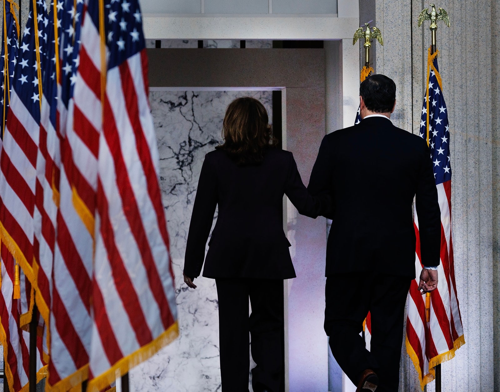 L'image peut contenir un drapeau américain, un drapeau, une personne adulte, une partie du corps, une main, des vêtements et un manteau.