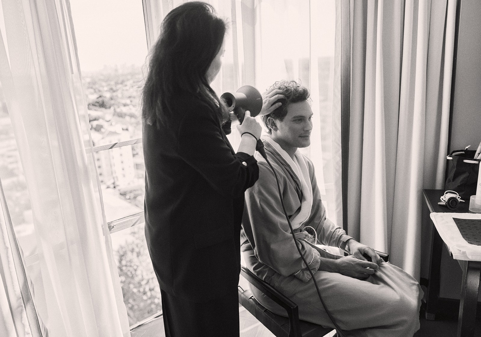 Cooper Koch a posé son téléphone et a récupéré un smoking Armani pour les Golden Globes 2025 L'image peut contenir Miloš Biković Personne adulte Photographie Appareil électrique Microphone Meubles et table de bureau