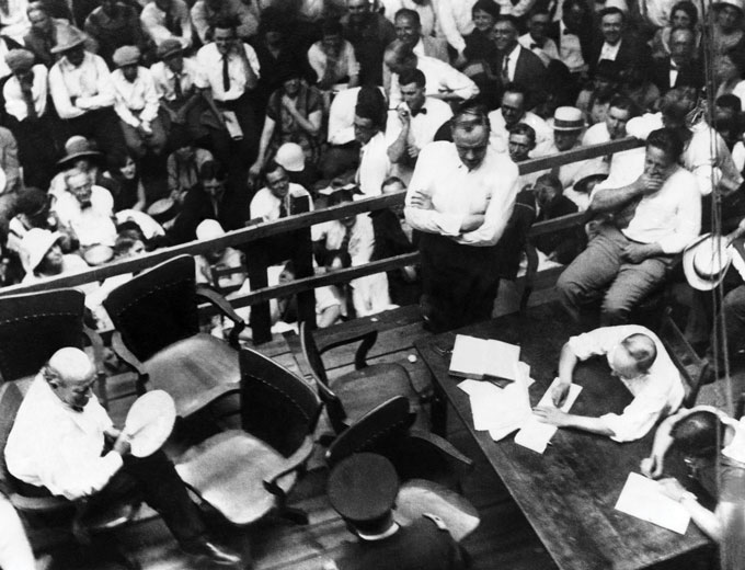 Une photo aérienne d'une personne écrivant sur un morceau de papier sur un bureau parmi une foule de gens.