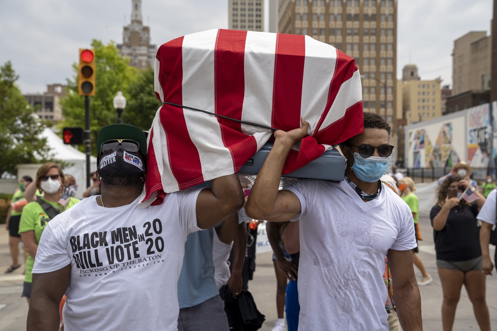 Deux hommes noirs tenant un cercueil vide recouvert d'un drapeau américain