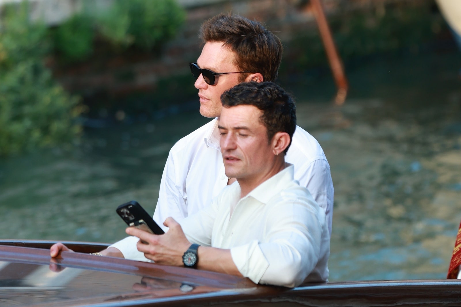 L'image peut contenir Orlando Bloom Tom Brady Wristwatch Personne adulte Téléphone mobile et accessoires