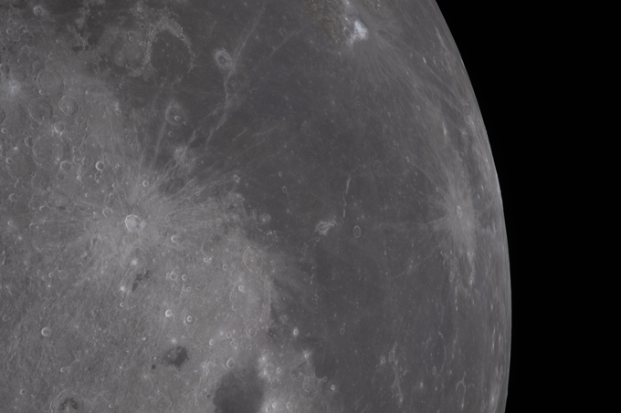 Le terrain plat et gris de la lune est ponctué de cratères lumineux entourés de rayons