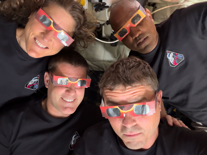 Quatre astronautes portent des lunettes à éclipse solaire.