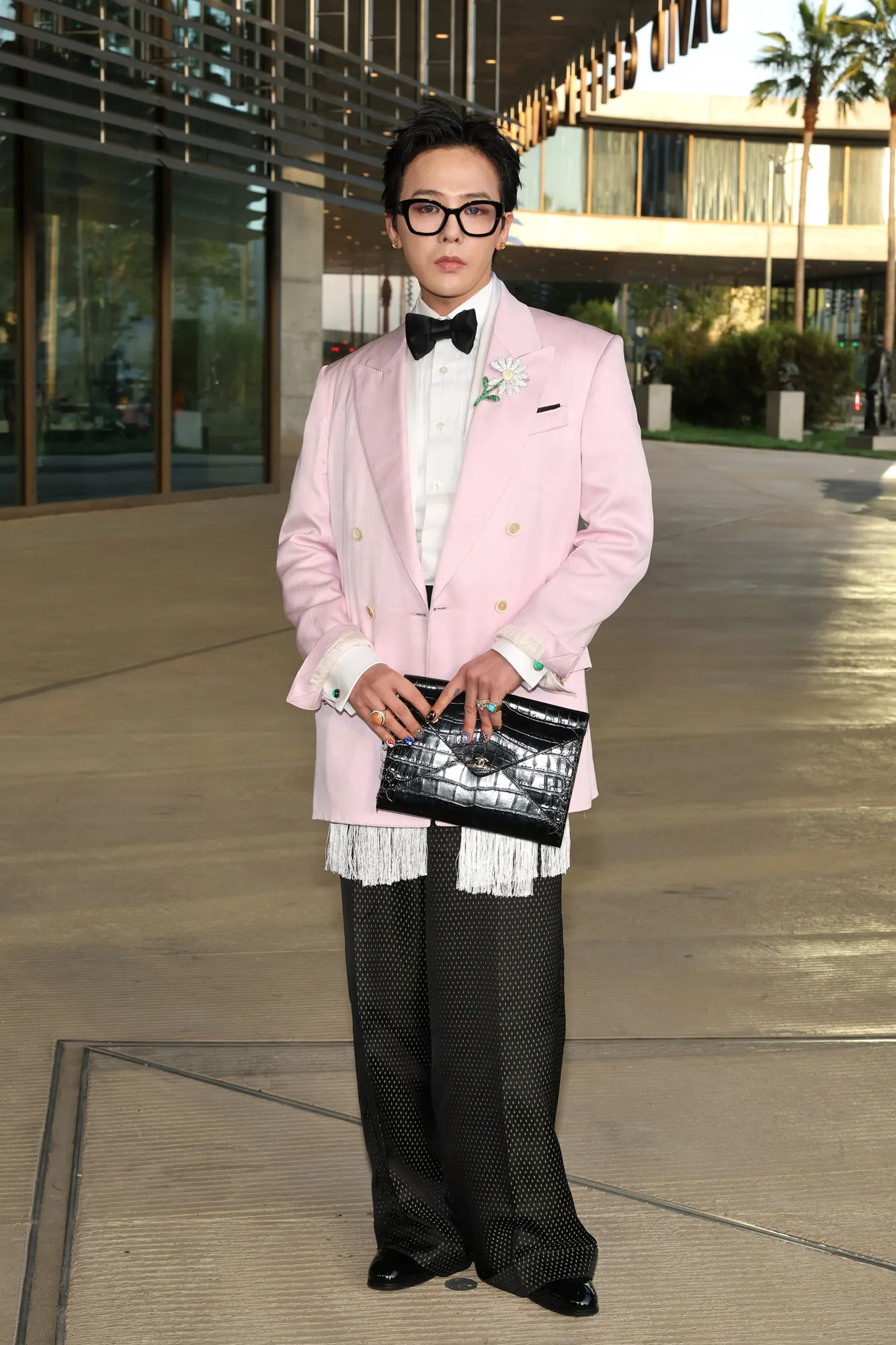 C'est le monde du LACMA et Hollywood veut y jouer L'image peut contenir des vêtements GDragon, tenue formelle, costume, blazer, manteau, veste, smoking, personne adulte et debout.