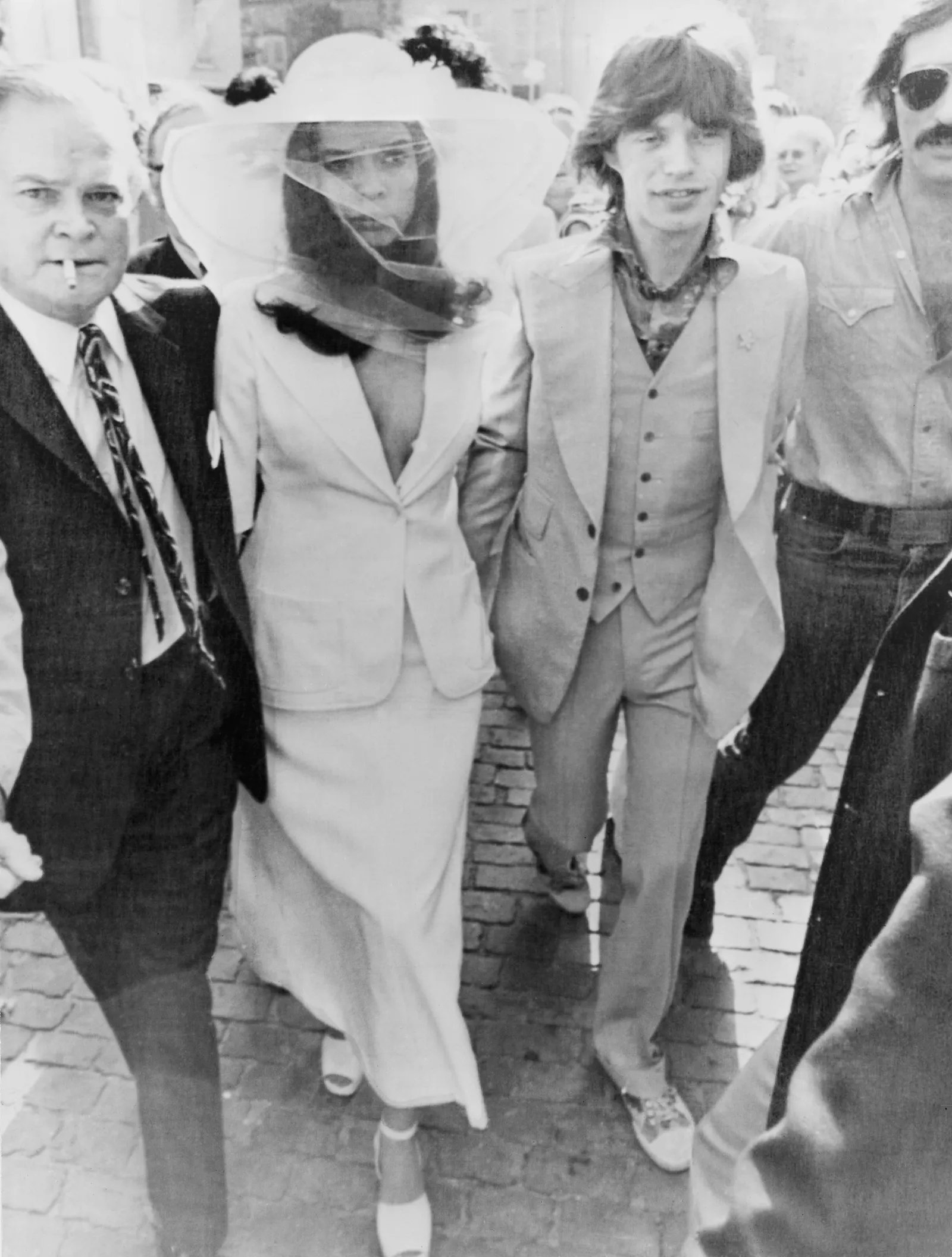 Dua Lipa se marie et rend un hommage mode à Bianca Jagger L'image peut contenir Bob Hope Bianca Jagger Mick Jagger Vêtements Tenue de soirée Costume Manteau Personne Adulte Visage et tête