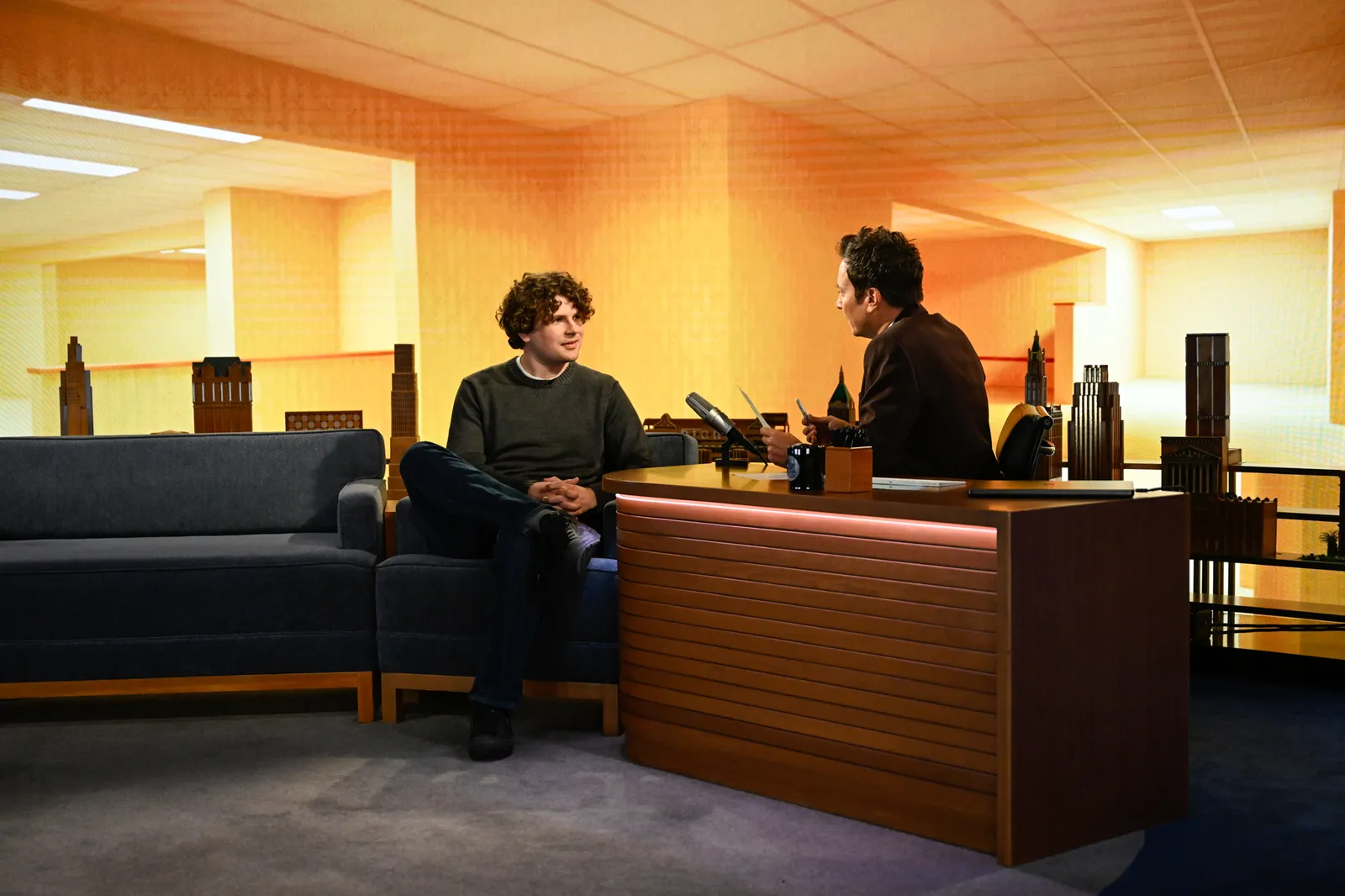 L'image contient peut-être Simon Amstell Jimmy Fallon Personne Adolescent Adulte Intérieur Meubles Table Vêtements Chaussures et chaussures