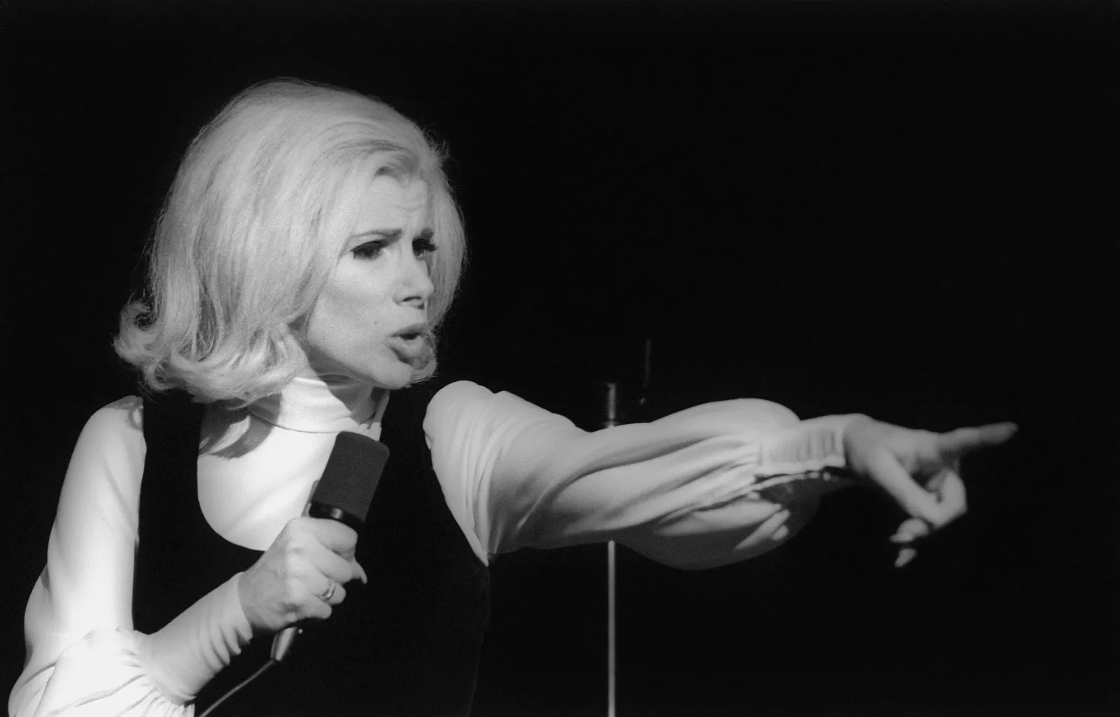 Comment la comédie a façonné l’histoire américaine, sans blague L'image peut contenir Joan Rivers Appareil électrique Microphone Partie du corps Doigt Main Personne Visage Tête et photographie