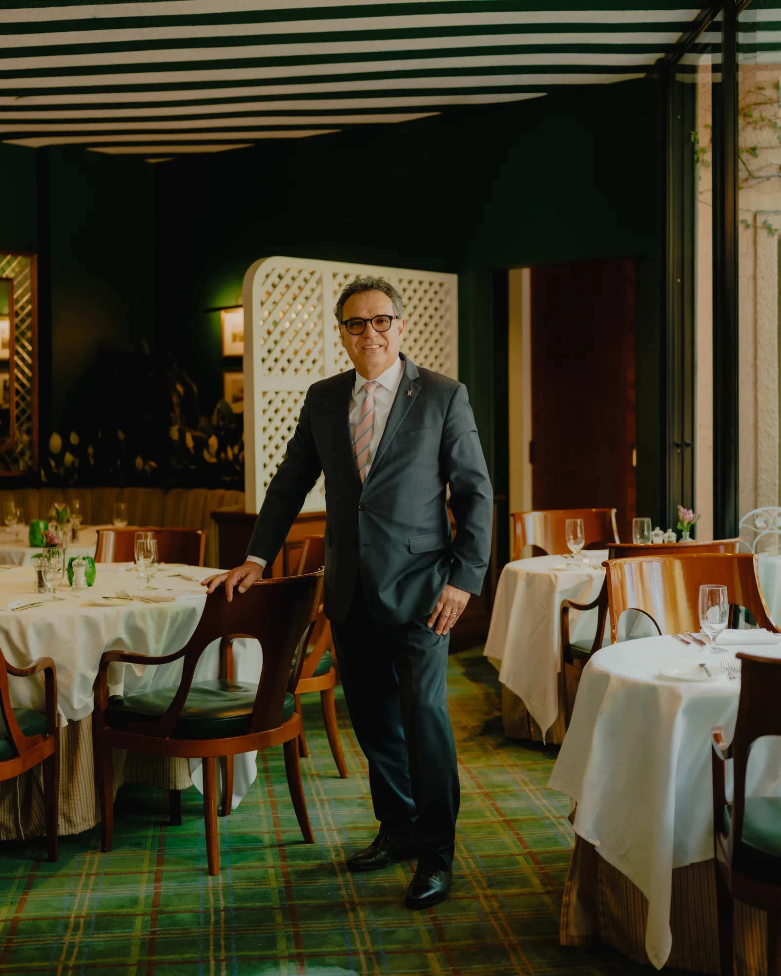 Le fonctionnement intérieur glamour du Polo Lounge, le lieu de déjeuner le plus puissant d'Hollywood L'image peut contenir une personne adulte, une chaise, des meubles, des vêtements, un manteau et une position debout.