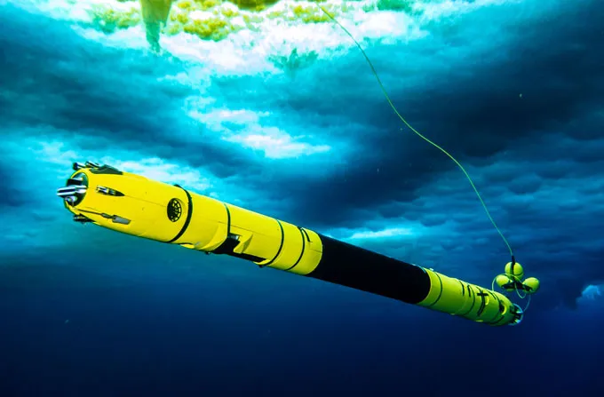 Un tube long et étroit, jaune aux extrémités et noir au milieu, flotte dans l'eau sous la glace. Il sera utilisé pour sonder la fonte des glaces au Groenland.