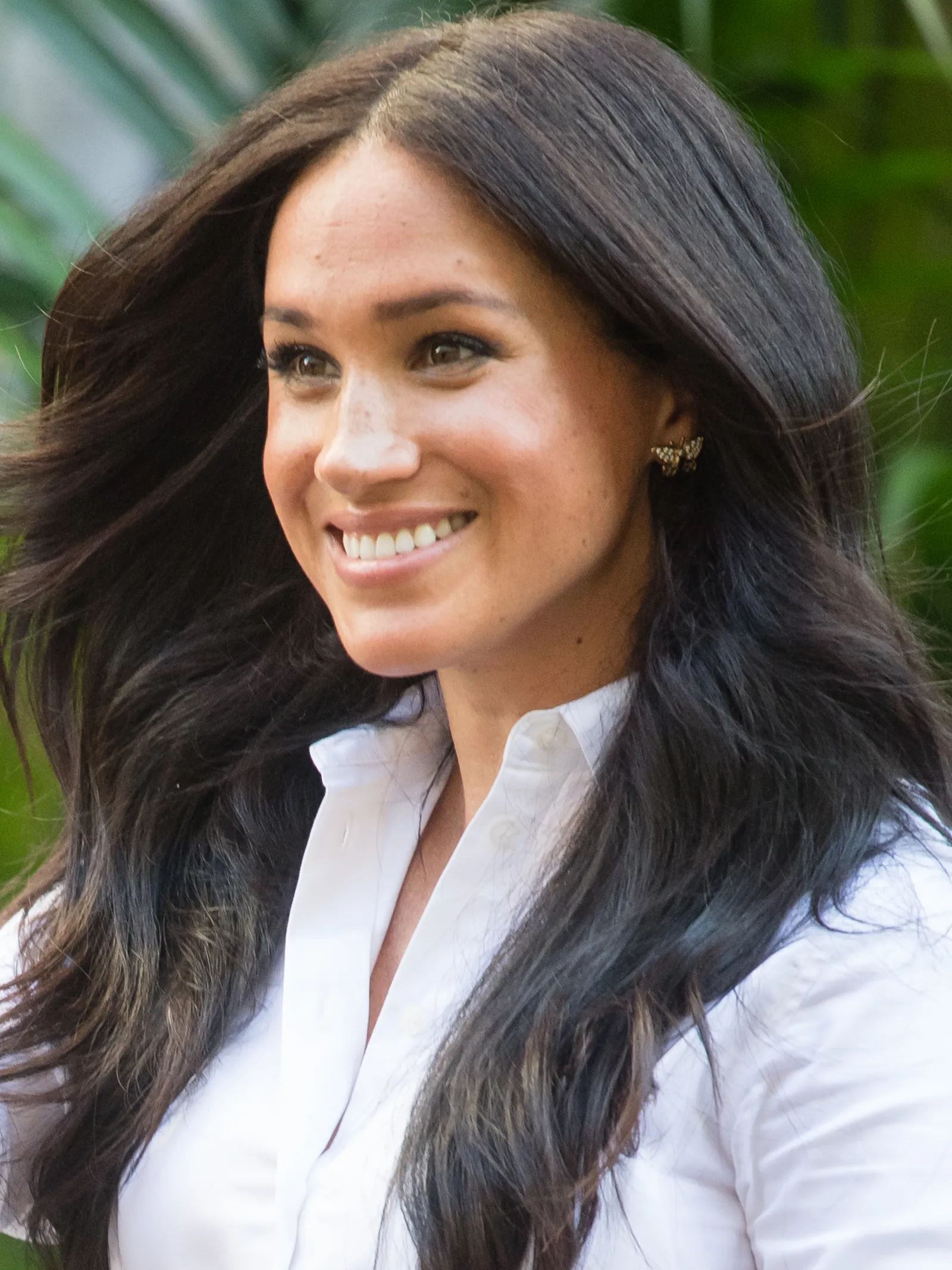 Meghan Markle rend hommage à la princesse Diana à travers ses boucles d'oreilles L'image peut contenir Meghan, duchesse de Sussex, tête de personne, visage, fossettes, sourire heureux, partie du corps, cou, adulte et vêtements.