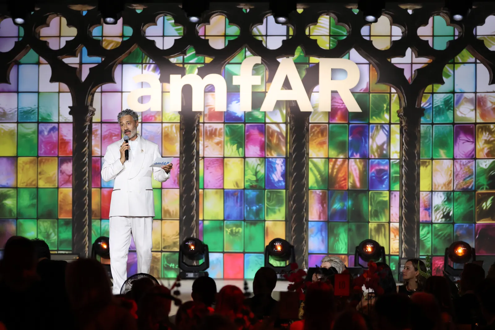 L’image peut contenir Taika Waititi Art Personne adulte Appareil électrique Microphone Éclairage de foule et vitraux