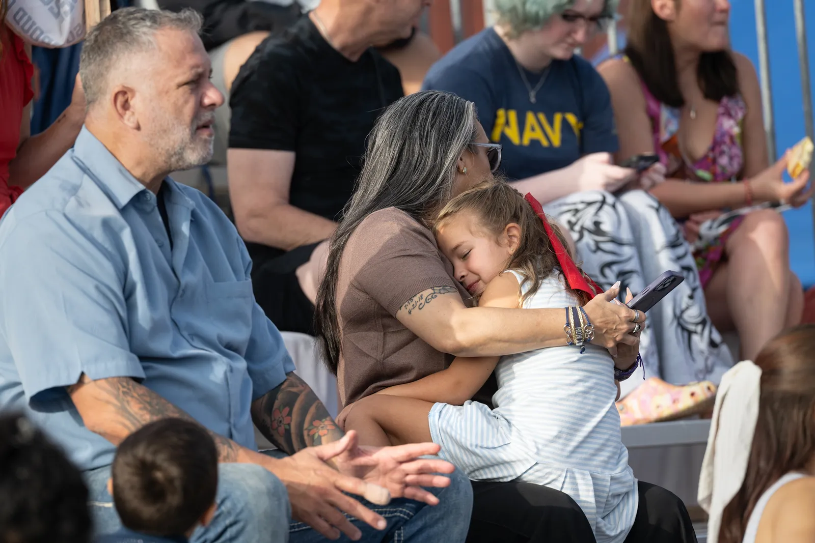 321 jours passés : chaos et cigarettes alors que l'USS Abraham Lincoln accoste à San Diego L'image contient peut-être une personne adulte qui fait un câlin à des personnes Accessoires Lunettes Bijoux et collier