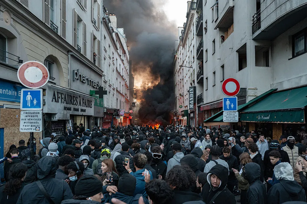 Emmanuel Macron s'adresse à la nation suite aux violentes manifestations à travers la France L'image peut contenir une personne adulte, un casque, des vêtements, un chapeau, des accessoires et des lunettes anti-émeute.