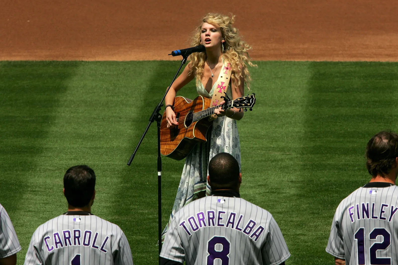 L'image peut contenir une guitare Taylor Swift, un instrument de musique, une personne adulte, un artiste, une performance solo et des accessoires.