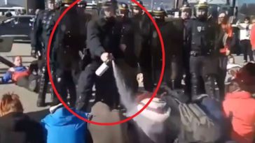 Un policier vide sa bombe lacrymogène sur des militants pacifiques pour le climat à Chambéry