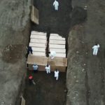 Aux Etats-Unis, des hommes en blouse creusent des tranchées pour enterrer les victimes pauvres ou sans famille