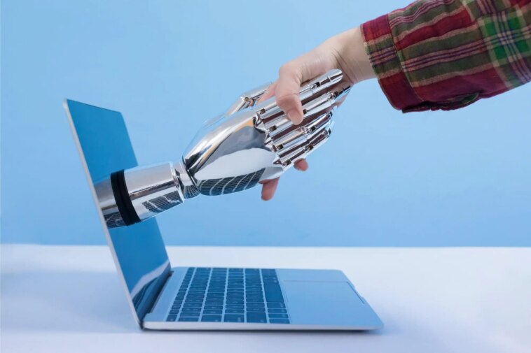 Les robots rendront-ils les travailleurs plus paresseux ? Human Robot Shaking Hands Laptop