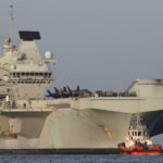 cc Rich Denton, modified, As part of Ex Khanjar Oman based near Duqm, Oman, soldiers of the Royal Irish Regiment and the Royal Scots Dragoons conducted Long Range Reconnaissance Patrol (LRRP) training in the desert, using their Foxhound, Jackal and Cayote fighting vehicles, they will be joined by the Carrier Strike Group and F35s of the Royal Air Force. Exercise Khanjar Oman will simulate the arduous desert conditions they will face when the battlegroup is deployed to Mali in 2022 as part of the UN MINUSMA mission., https://commons.wikimedia.org/wiki/File:HMS_Queen_Elizabeth_Duqm_Port_Oman.jpg