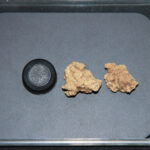 Deux anciens grains de fromage sur une assiette à côté d'un bouchon de bouteille, qui a à peu près la même taille.