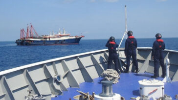 Philippine Coast Guard personnel survey several ships believed to be Chinese militia vessels in Sabina Shoal in the South China Sea, in a handout photo distributed by the Philippine Coast Guard on 5 May and taken according to source on 27 April 2021., modified, Philippines Coast Guard, https://commons.wikimedia.org/w/index.php?sort=last_edit_desc&search=china+maritime+militia+filetype%3Abitmap&title=Special%3ASearch&profile=advanced&fulltext=1&advancedSearch-current=%7B%22fields%22%3A%7B%22filetype%22%3A%22bitmap%22%7D%7D&ns0=1&ns6=1&ns12=1&ns14=1&ns100=1&ns106=1#/media/File:Philippine_coast_guard-COFTLDK4CRL5LFGQLAVIYGDEQE.jpg