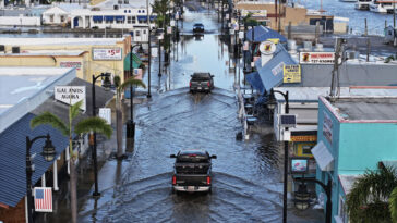 Des camions circulent dans une rue inondée.