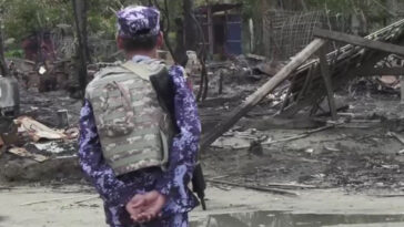 cc Steve Sandford (VOA), modified, https://commons.wikimedia.org/w/index.php?limit=500&offset=0&profile=default&search=myanmar+conflict&title=Special:Search&ns0=1&ns6=1&ns12=1&ns14=1&ns100=1&ns106=1#/media/File:BGP_officer_near_a_burnt_down_house_in_Rakhine_State.jpg