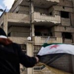 La géopolitique dégèle la guerre civile syrienne A man waves the old Syrian flag in front of the former police st, cc Flickr Freedom House, modified, https://creativecommons.org/licenses/by/2.0/