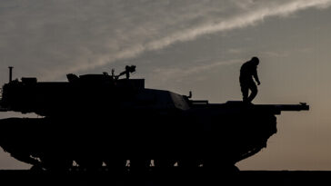 US Department of Defense, modified, https://flickr.com/photos/39955793@N07/32649549600/in/photolist-RK8tAY-SGx79L-2hnxwzi-2hoBH5Z-NBzcca-CnEW3H-2d8ski9-SKVrmi-L2JXRf-GS6m3q-BsRQEX-Uh2dxm-28aUrRx-2h6ktLp-9BferH-H1RkdU-2b7vzDv-GXYy5a-H8f56x-SV86Rm-ESayYV-Na5A39-p3krCL-26ZcxjF-GKxbvv-EokbtN-2gfJAT1-2mku2RW-2hFcdsR-BkyzDg-UeFS5Y-p576n4-tJJaHf-GvFL6B-ANcNof-GRt7Qv-oqNWir-GRoQKQ-2nkioFs-GZE8eB-L8MKvF-G5ik46-tJHvYq-HocBV1-8cgPZG-2oh8Z63-md1wjR-MYhHRt-2gznMr9-u1X6Gu, A U.S. Soldier with 1st Battalion, 8th Infantry Regiment, 3rd Armored Brigade Combat Team, 4th Infantry Division, prepares to offload M1A2 Abrams tanks at Mihail Kogalniceanu Air Base, Constanta County, Romania, Feb 14, 2017. The equipment was brought to Romania in support of Operation Atlantic Resolve, a demonstration of continued U.S. commitment to collective security through a series of actions designed to reassure NATO allies and partners of America