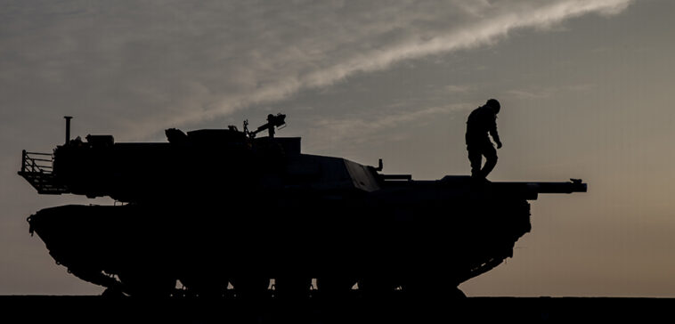 US Department of Defense, modified, https://flickr.com/photos/39955793@N07/32649549600/in/photolist-RK8tAY-SGx79L-2hnxwzi-2hoBH5Z-NBzcca-CnEW3H-2d8ski9-SKVrmi-L2JXRf-GS6m3q-BsRQEX-Uh2dxm-28aUrRx-2h6ktLp-9BferH-H1RkdU-2b7vzDv-GXYy5a-H8f56x-SV86Rm-ESayYV-Na5A39-p3krCL-26ZcxjF-GKxbvv-EokbtN-2gfJAT1-2mku2RW-2hFcdsR-BkyzDg-UeFS5Y-p576n4-tJJaHf-GvFL6B-ANcNof-GRt7Qv-oqNWir-GRoQKQ-2nkioFs-GZE8eB-L8MKvF-G5ik46-tJHvYq-HocBV1-8cgPZG-2oh8Z63-md1wjR-MYhHRt-2gznMr9-u1X6Gu, A U.S. Soldier with 1st Battalion, 8th Infantry Regiment, 3rd Armored Brigade Combat Team, 4th Infantry Division, prepares to offload M1A2 Abrams tanks at Mihail Kogalniceanu Air Base, Constanta County, Romania, Feb 14, 2017. The equipment was brought to Romania in support of Operation Atlantic Resolve, a demonstration of continued U.S. commitment to collective security through a series of actions designed to reassure NATO allies and partners of America