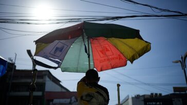 À Manille, un homme ouvre un parapluie pour se protéger du soleil.