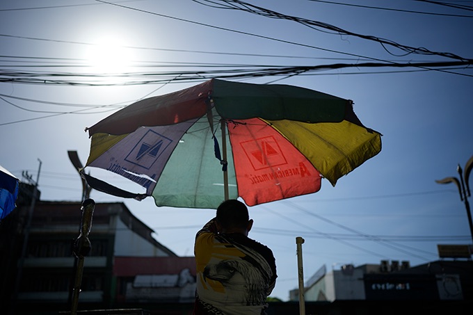 À Manille, un homme ouvre un parapluie pour se protéger du soleil.
