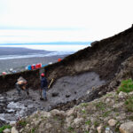 Des chercheurs sont montrés debout sur une parcelle de glace glaciaire exposée, au milieu d'un glissement de terrain.