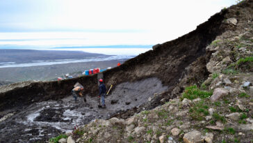 Des chercheurs sont montrés debout sur une parcelle de glace glaciaire exposée, au milieu d'un glissement de terrain.