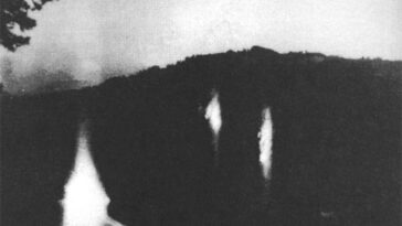 Trois lumières flottant dans un cadre sombre, sur une photo en noir et blanc.