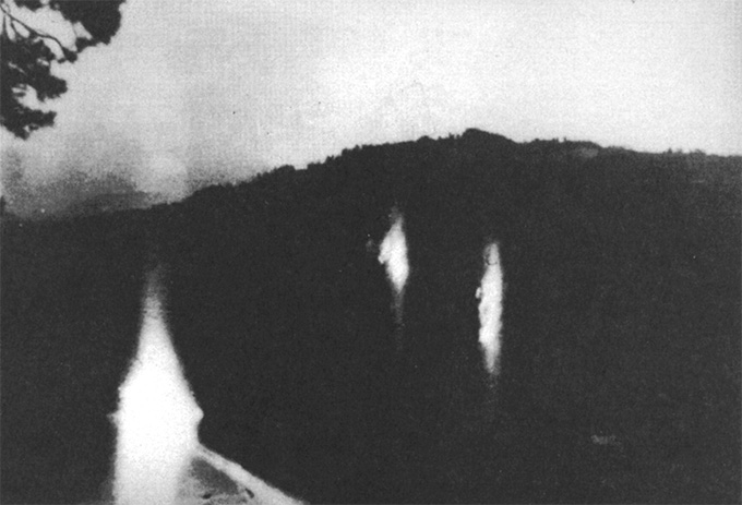 Trois lumières flottant dans un cadre sombre, sur une photo en noir et blanc.