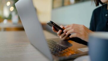 Woman working on laptop and phone