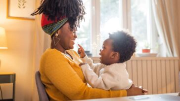 Single mother with son at home. She is using computer for paying bills or online shopping.