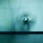 Couple waiting at airport Description Couple sitting, waiting at the airport behind small squared glass wall, evoking a mirage, memory and dreams in blue and grey tones. Zurich, Switzerland. 2009