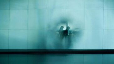 Couple waiting at airport Description Couple sitting, waiting at the airport behind small squared glass wall, evoking a mirage, memory and dreams in blue and grey tones. Zurich, Switzerland. 2009
