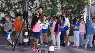 Les enfants et les parents se sont rassemblés autour d'un télescope.