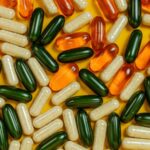 A pile of colourful supplement pills lying on a yellow table top.