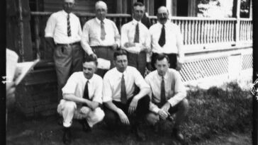 Une photo de sept personnes posant pour un portrait devant un porche.