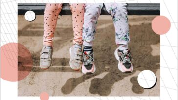 Two little girls best friends, children, sisters sit on a wooden bench in the park outdoors.