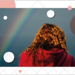 Rear view of woman wearing a red hoodie under a rainbow