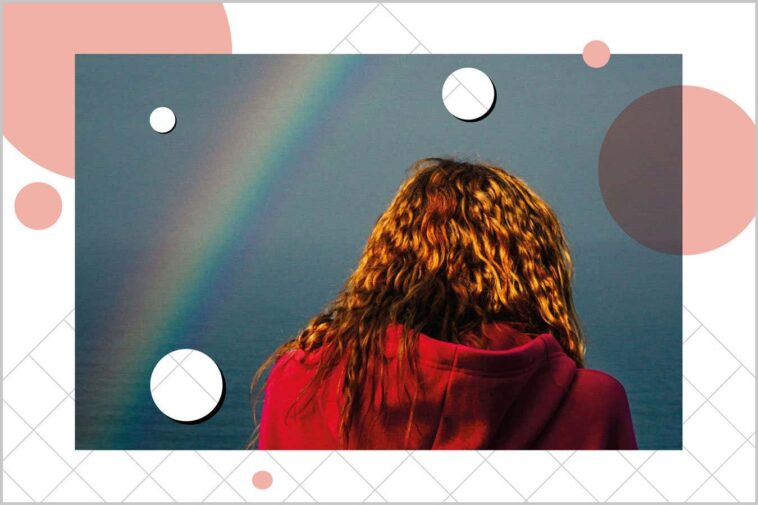 Rear view of woman wearing a red hoodie under a rainbow