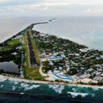 FUNAFUTI, TUVALU - NOVEMBER 28: An aerial view of downtown and the airport runway, between the Pacific Ocean (L) and lagoon (R), on November 28, 2019 in Funafuti, Tuvalu. The??low-lying??South Pacific island nation??of about 11,000 people has been classified as ???extremely vulnerable??? to climate change by the??United Nations Development Programme.??The world???s fourth-smallest country is struggling to cope with climate change related impacts including five millimeter per year sea level rise (above the global average), tidal and wave driven flooding, storm surges, rising temperatures, saltwater intrusion and coastal erosion on its nine coral atolls and islands, the highest of which rises about 15 feet above sea level. In addition, the severity of cyclones and droughts in the Pacific Island region are forecast to increase due to global warming. Some scientists have predicted that Tuvalu could become inundated and uninhabitable in 50 to 100 years or less if sea level rise continues.??The country is working toward a goal of 100 percent renewable power generation by 2025 in an effort to curb pollution and set an example for larger nations. Tuvalu is also exploring a plan to build an artificial island. (Photo by Mario Tama/Getty Images)