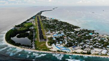 FUNAFUTI, TUVALU - NOVEMBER 28: An aerial view of downtown and the airport runway, between the Pacific Ocean (L) and lagoon (R), on November 28, 2019 in Funafuti, Tuvalu. The??low-lying??South Pacific island nation??of about 11,000 people has been classified as ???extremely vulnerable??? to climate change by the??United Nations Development Programme.??The world???s fourth-smallest country is struggling to cope with climate change related impacts including five millimeter per year sea level rise (above the global average), tidal and wave driven flooding, storm surges, rising temperatures, saltwater intrusion and coastal erosion on its nine coral atolls and islands, the highest of which rises about 15 feet above sea level. In addition, the severity of cyclones and droughts in the Pacific Island region are forecast to increase due to global warming. Some scientists have predicted that Tuvalu could become inundated and uninhabitable in 50 to 100 years or less if sea level rise continues.??The country is working toward a goal of 100 percent renewable power generation by 2025 in an effort to curb pollution and set an example for larger nations. Tuvalu is also exploring a plan to build an artificial island. (Photo by Mario Tama/Getty Images)