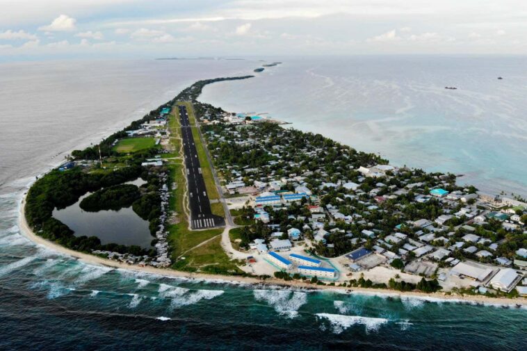 FUNAFUTI, TUVALU - NOVEMBER 28: An aerial view of downtown and the airport runway, between the Pacific Ocean (L) and lagoon (R), on November 28, 2019 in Funafuti, Tuvalu. The??low-lying??South Pacific island nation??of about 11,000 people has been classified as ???extremely vulnerable??? to climate change by the??United Nations Development Programme.??The world???s fourth-smallest country is struggling to cope with climate change related impacts including five millimeter per year sea level rise (above the global average), tidal and wave driven flooding, storm surges, rising temperatures, saltwater intrusion and coastal erosion on its nine coral atolls and islands, the highest of which rises about 15 feet above sea level. In addition, the severity of cyclones and droughts in the Pacific Island region are forecast to increase due to global warming. Some scientists have predicted that Tuvalu could become inundated and uninhabitable in 50 to 100 years or less if sea level rise continues.??The country is working toward a goal of 100 percent renewable power generation by 2025 in an effort to curb pollution and set an example for larger nations. Tuvalu is also exploring a plan to build an artificial island. (Photo by Mario Tama/Getty Images)