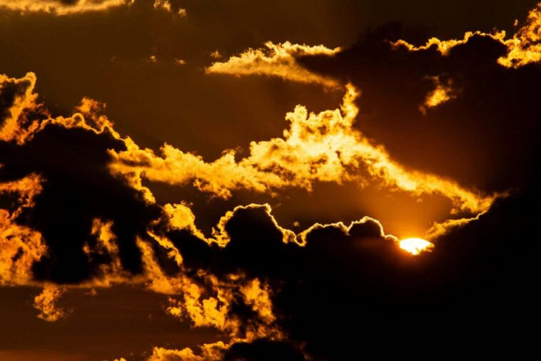 /fiery-sunset-glows-through-dramatic-dark-clouds